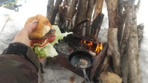 una persona sosteniendo un sándwich frente al fuego en Ski base en Akaigawa