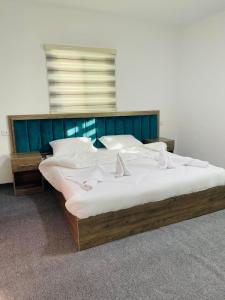 a large bed with white sheets and a blue headboard at Grandpa House in Wadi Musa