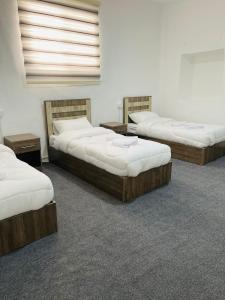 three beds are lined up in a room at Grandpa House in Wadi Musa