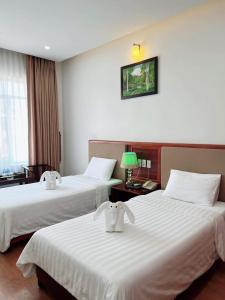 a hotel room with two beds with white sheets at Bình Minh Hotel in Hà Tĩnh