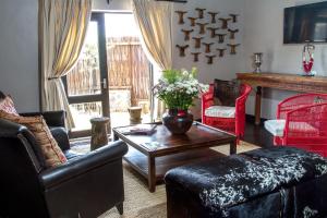 sala de estar con sofá, mesa y chimenea en Riverstone Lodge, en Muldersdrift