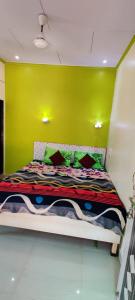 Bett in einem Zimmer mit gelber Wand in der Unterkunft Alpha House Matheran in Matheran