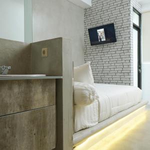 a bedroom with a white bed and a brick wall at DParagon Jakarta Timur in Jakarta