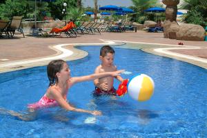 two children playing with a beach ball in a pool at Nissiana Hotel & Bungalows in Ayia Napa