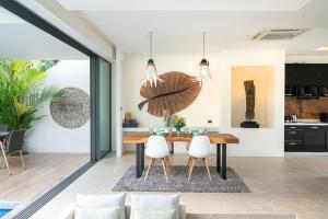 Il comprend une cuisine et une salle à manger avec une table en bois et des chaises blanches. dans l'établissement Cozy Pool Villa Naiyang Beach, à Ban Sakhu