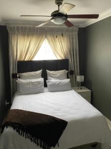 1 dormitorio con 1 cama grande y ventilador de techo en No 21 Marina Palms, en Hibberdene