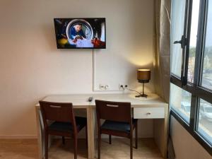 a room with a desk with two chairs and a tv on the wall at Appart'Hotel - Gare TGV - Courtine - Confluence - 218 in Avignon
