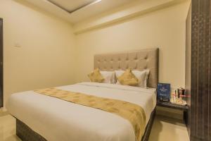 sypialnia z dużym białym łóżkiem ze złotymi poduszkami w obiekcie Hotel Palace Inn Near Don Bosco -Borivali- Metro Station w Bombaju