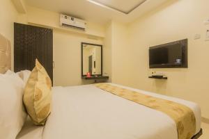 ein Schlafzimmer mit einem großen weißen Bett und einem TV in der Unterkunft Hotel Palace Inn Near Don Bosco -Borivali- Metro Station in Mumbai