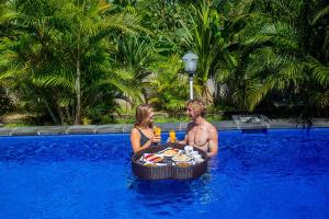 a man and a woman sitting in a swimming pool at Tatak Bunut Private Villa in Nusa Lembongan