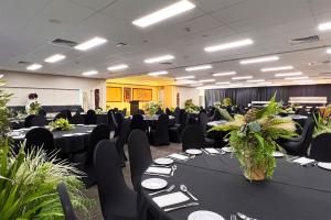 a banquet hall with black tables and chairs and plants at Sudima Hotel Lake Rotorua in Rotorua