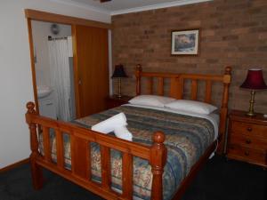 a bedroom with a wooden bed with two pillows at Grampians View Cottages and Units in Halls Gap