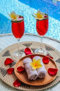 a plate of food with two wine glasses and flowers at Le Cielo Romantic Villas by Maviba in Seminyak