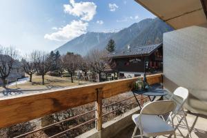 a balcony with two chairs and a table and a building at Appartement Flégère et Golf - Happy Rentals in Chamonix-Mont-Blanc