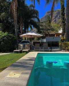 a swimming pool with a table and an umbrella at Hospedaje Casa Teotleco in Tepoztlán