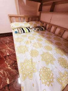 a bed with a yellow and white blanket on it at D' ALORA Transient House in Daet
