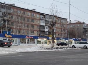 un estacionamiento con autos estacionados frente a un edificio en 1 комнатные апартаменты на Садуакасова 24, en Kokshetau