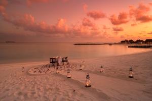 - une table et des chaises sur une plage éclairée dans l'établissement VARU by Atmosphere - Premium All Inclusive with Free Transfers, à Atoll Malé Nord