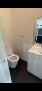 a white bathroom with a toilet and a sink at Spirit of Bondi Apartments in Sydney