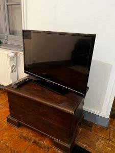 a flat screen tv sitting on top of a wooden chest at La persienne Bleue - Coeur historique de Mortagne au Perche in Mortagne-au-Perche