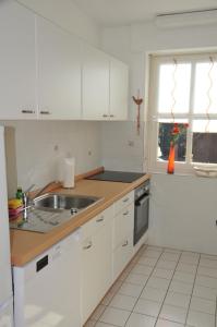 a kitchen with white cabinets and a sink and a window at Haus Jodokus, Whg Professor Paljass in Kellenhusen