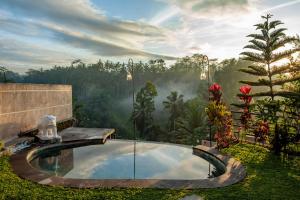 a pool in a garden with a view of a forest at Campuhan Sebatu Resort in Tegalalang