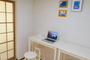 un computer portatile seduto su una scrivania bianca con sgabello di Aoisora Aoiumi no guest house - Vacation STAY 74840v a Takamatsu