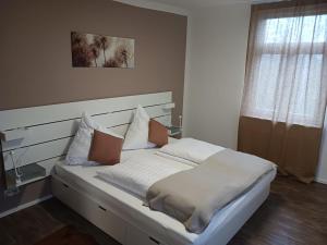 a bed with white sheets and pillows in a room at Gasthaus Wilhelmshöhe in Wasserburg am Bodensee