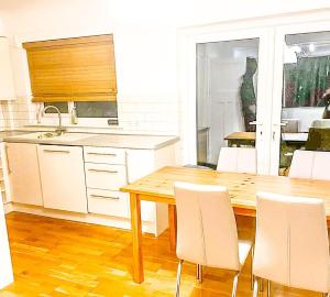 a kitchen with a wooden table and white chairs at 3-Bed House in London Garden & free parking in Dartford