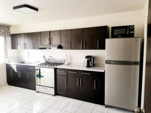 eine Küche mit Holzschränken und einem Kühlschrank in der Unterkunft Tu Casa de Familia in Tijuana