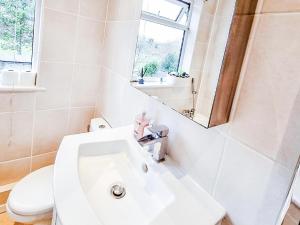 Baño blanco con lavabo y aseo en 3-Bed House in London Garden & free parking en Dartford