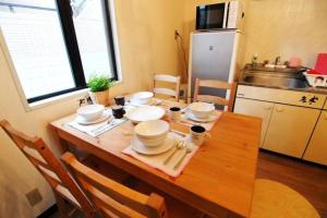kuchnia z drewnianym stołem i naczyniami w obiekcie Maihama Ushio Lodge 潮ロッヂ Room 101 w mieście Urayasu