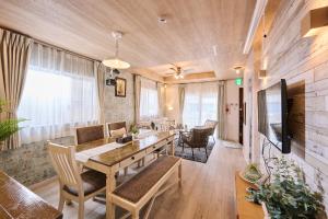 een woonkamer met een houten tafel en een bank bij ペンション マカナレアリゾート沖縄 in Ginowan