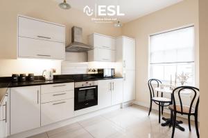 a kitchen with white cabinets and a table and chairs at Elegant Apartment on Historic Cobbled High St Shrewsbury Town Centre in Shrewsbury