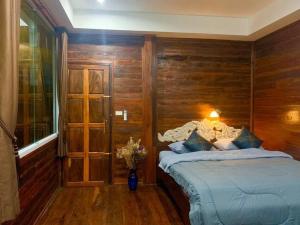 a bedroom with a bed with a wooden wall at Une Jai Place เรือนอุ่นใจ in Phimai