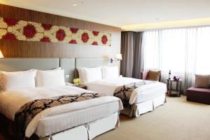 a hotel room with two beds and a couch at Golden Tulip Zhong Xin Hotel Taichung in Taichung