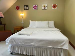 a large white bed in a bedroom with pictures on the wall at Nawaporn Place in Phuket