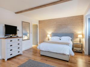 a bedroom with a large bed and a flat screen tv at The Little Barn in Woolverstone