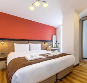 a bedroom with a large white bed with a red wall at BayMari Suites City Life in Istanbul
