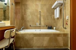 a bathroom with a tub with a shower and a sink at Hotel Metropolitan Premier Taipei in Taipei