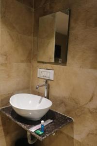een badkamer met een witte wastafel en een spiegel bij Hotel Pub Street Inn in Navi Mumbai