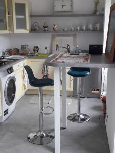 uma cozinha com um lavatório e dois bancos de bar em Les Tilleuls em Plestin-les-Grèves