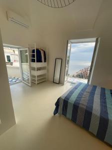 a white bedroom with a bed and a large window at La Pigolina in Positano