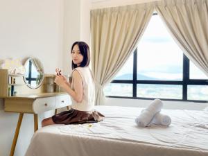una mujer sentada en una cama frente a un espejo en Modern Muji Inspired Design, Bandar Menjarala, near to DesaParkCity 2 Bedrooms Suite, en Kuala Lumpur