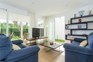 a living room with two blue chairs and a tv at Villa Jamaica in Fornells