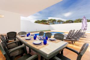 a dining table with chairs and a pool at Villa Jamaica in Fornells