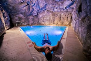 a man laying in a swimming pool in a cave at Narzissen Vital Resort Bad Aussee in Bad Aussee