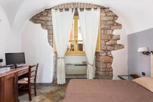 a bedroom with a bed and a desk and a window at Locanda di Corte in Bosa