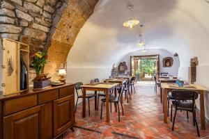 a dining room with tables and chairs and a stone wall at Locanda di Corte in Bosa