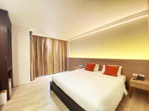 um quarto com uma grande cama branca e 2 almofadas laranja em Srilamduan Hotel em Si Sa Ket